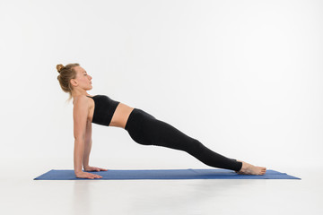 Sporty attractive young woman doing yoga practice on white background.