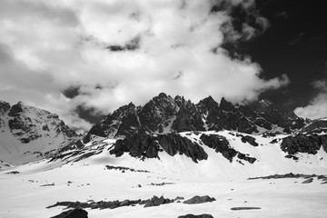 High sunlit rocks, snowy plateau and cloudy sky