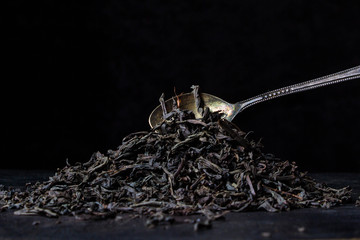 loose leaf tea on a black background and a teaspoon