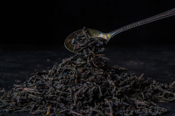 loose leaf tea on a black background and a teaspoon