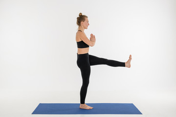 Sporty attractive young woman doing yoga practice on white background.