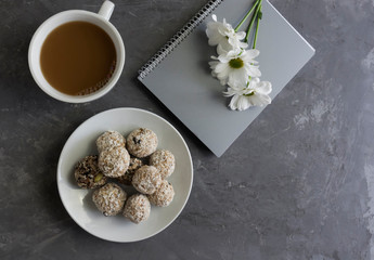 Good morning concept, workplace, notebook and fresh flowers with a cup of coffee and energy balls, healthy sweets, protein balls.