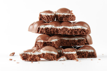 Composition of bars and pieces of porous milk chocolate with a coconut layer closeup on a white background isolated