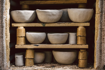 Fototapeta na wymiar Viele rustikale Schalen aus Ton im Brennofen. Rohe Keramikprodukte ohne Glasur, Ansicht. Kunstgewerbe, Hobby und Lifestyle
