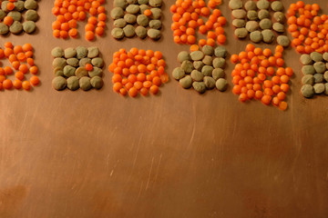 Grains of orange and green lentils on a copper surface. Geometric pattern. Copy space. 