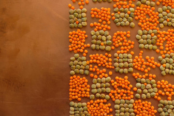 Grains of orange and green lentils on a copper surface. Geometric pattern. Copy space. 