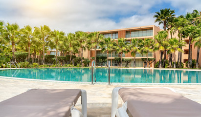 Modern luxurious pool with clean, clear, blue water and sun loungers on site.