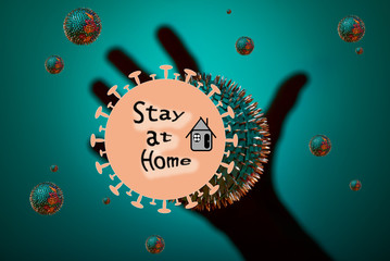 Inscription Stay at Home on green background with a hand. Virus around the world. stay at home. the danger is near. green bacterium. the plate with letters