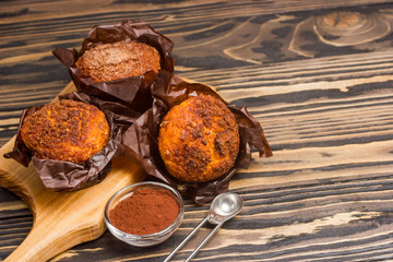 Homemade delicious muffins ith cacao on wooden background close-up