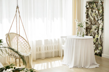 beautiful bright interior with hanging chair and floral decor