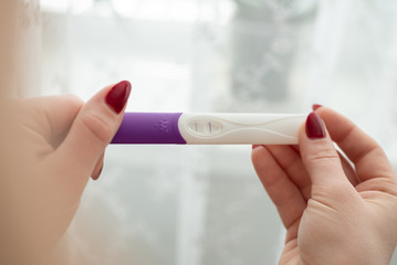 Pregnancy test in female hand on blurred background