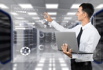 Businessman holding laptop and touching icons on background