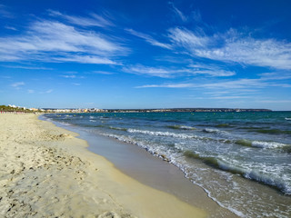 A wide sandy beach, the Mediterranean Sea with small waves and a bright blue sky. 
The deserted beaches of Spain are a crisis of international tourism.