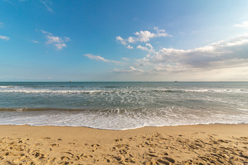 Beautiful tropical beach with sand, ocean wave against blue sky, clouds and horizon in sunny day. Nature and summer vacation concept.