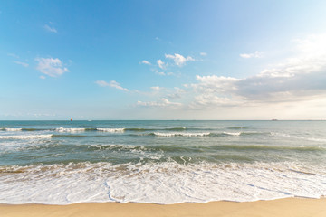 Beautiful tropical beach with sand, ocean wave against blue sky, clouds and horizon in sunny day. Nature and summer vacation concept.