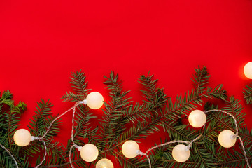Christmas garland on branches of spruce on red background. round lights decorate Christmas tree. Concept of blank frame, copy space. Christmas or new year flatlay background.