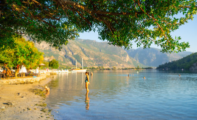 sea beach with green tree turquoise water mountain view people in water