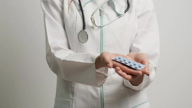 Female doctor holding treatment pills in front of the camera