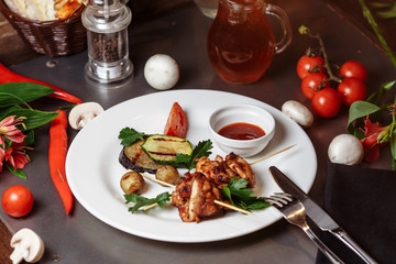 Barbecued marinated turkey or chicken meat shish kebab skewers with ketchup sauce and grilled vegetables on rustic wooden table background. Traditional barbecue grill food
