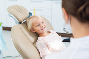 A cute little girl at the dentist's office and a doctor in the f