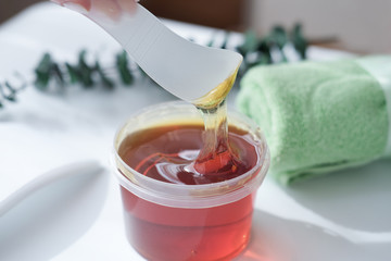  sugar paste or wax honey for hair removing flows down from waxing spatula stick. beauty spa concept.