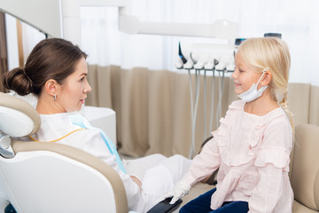 Fototapeta premium A little girl sitting and smiling in a dental clinic, while play
