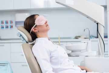 Fototapeta premium A young woman, a dentist or a patient, lies on the chair in the