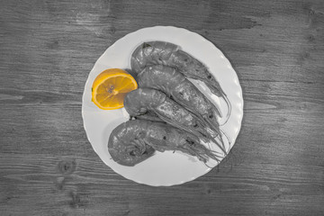 Color isolation effect of prawns with lemon on wooden background. Concept: cuisine based on fish,...