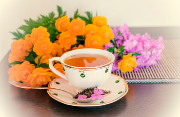 A Cup of tea and a bouquet of pink and orange flowers.