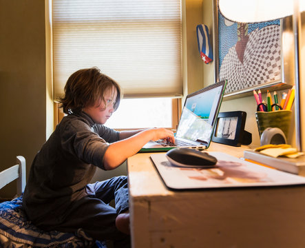 6 year old boy sitting at his desk during a remote schooling session