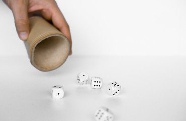 Rolling white dices with brown leather cup