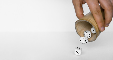 Rolling white dices with brown leather cup