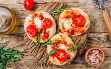 Pizzete. Home baked mini pizzas bologneseon cutting board. Tomato sauce ,mozzarella cheese and minced meat. Rustic wooden table. Top view. Stay at home concept
