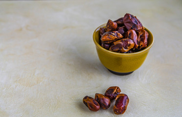 Dried fruit dates in a green bowl, on marble background.