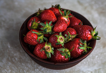 Fresh strawberries in a bowl on a marble background with a discreet scene.