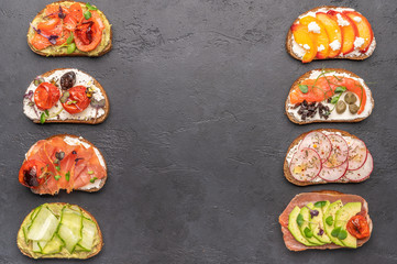 Homemade sandwiches with bread and various ingredients and spices on a dark background. Healthy delicious food for breakfast and lunch