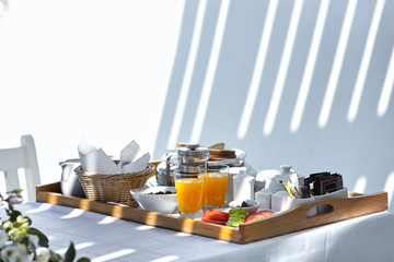 Fototapeta na wymiar Room service mediterranean breakfast served outdoors on a white terrace. Coffee, orange juice, sandwich, egg served on a tray