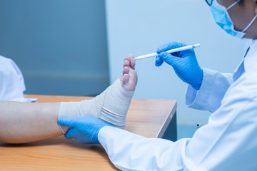 Close-up hand wear medical gloves doctor examines the leg of the woman’s heel for heel spurs,...