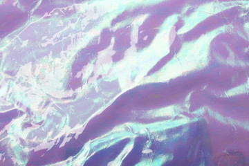 Holographic bright rainbow multicolor real crumpled texture background in light blue - purple toned.
