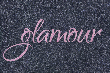 Glamour lettering word light pink (ballet slipper) on gray (midnight blue black) glitter texture. Shiny sparkle background