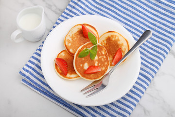 Pancake in a plate with strawberries decorated with mint on a marble background