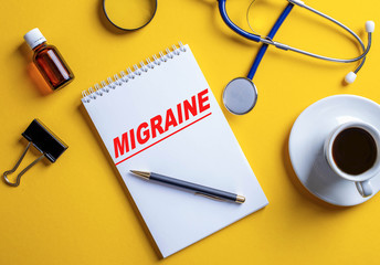 The word migraine is written in a white notebook on a yellow background.