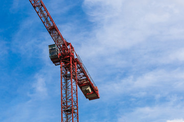  Red tower crane against blue sky with white clouds. Close up. Copy space.