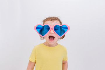 A beautiful little girl in big funny glasses screams and laughs on a white background with space for text. Day of laughter.