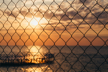 Ocean sunset behind a fence