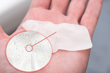 Close-up nose blackheads or black dots remove from pore of nose, clear-up strips on hand as example, macro cosmetic pore strips. 