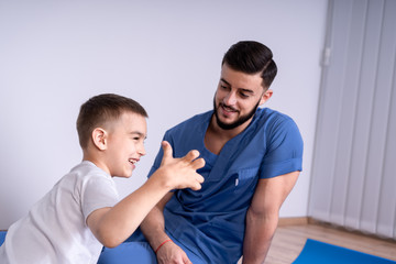 Fototapeta premium A little boy stands beside his doctor, and together they show a sign of class, concept of treatment and friendship