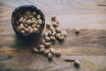 roasted pistachios in a rustic bowl on wooden serving tray
