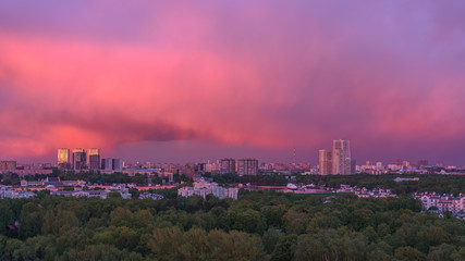 Colourful sunset over Moscow city. Amazing purple vibrant colors of the sky, colourful scenery of the park, river with luxury yachts, sunlit buildings. 