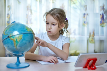 Girl looking at the globe while doing homework